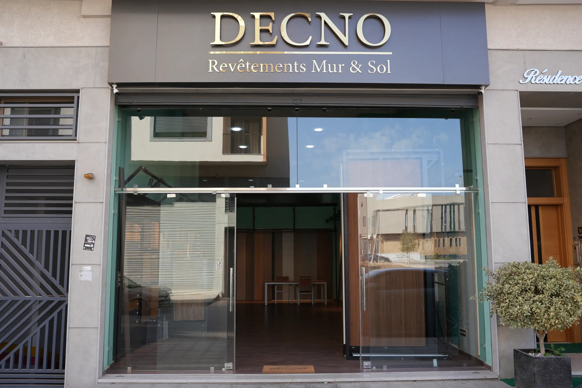 La devanture du showroom DECNO à Ain Chock, Casablanca : enseigne dorée « DECNO — Revêtements Mur & Sol » au-dessus d'une vitrine toute hauteur